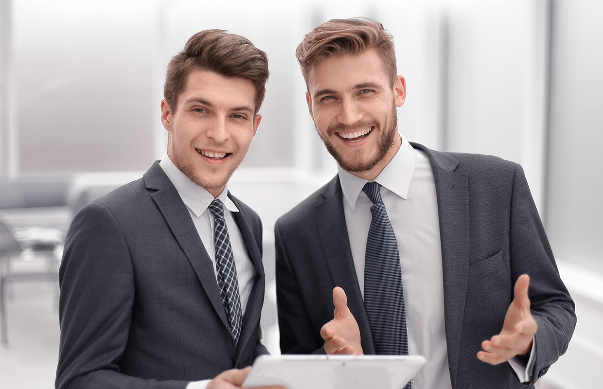 Dois homens investidores, de terno e gravata, olhando de frente para foto.