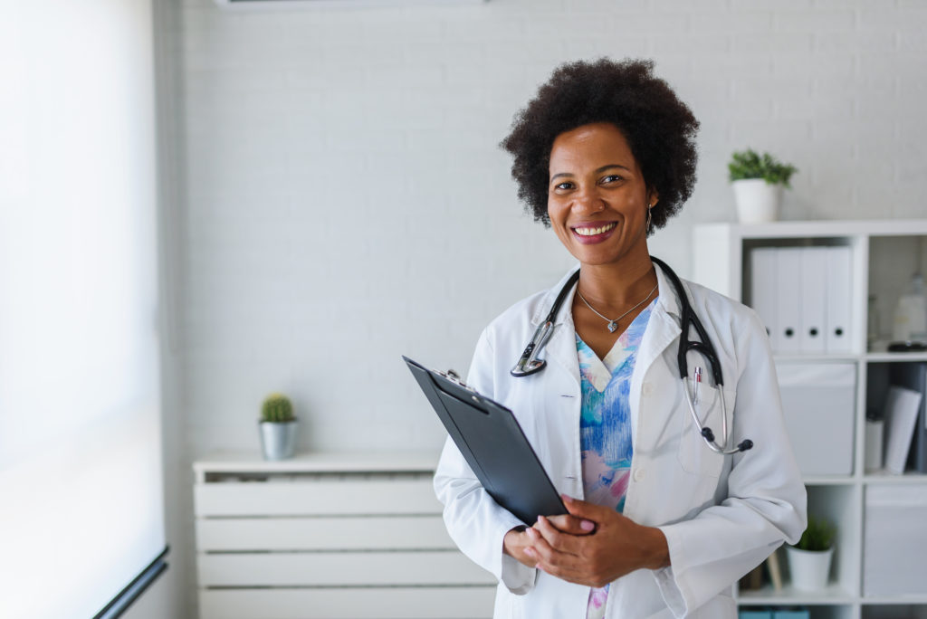 Retrato de uma médica afro-americana de pé em seu consultório. 